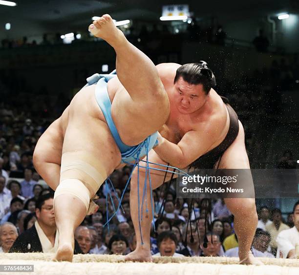 Mongolian grand champion Hakuho sends komusubi Kotoyuki flying to the sandy surface on the sixth day of the Nagoya Grand Sumo Tournament at Aichi...