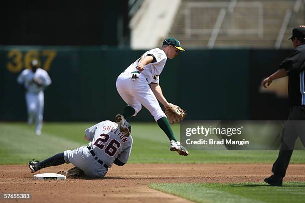 Mark Ellis of the Oakland Athletics leaps as Chris Shelton slides during the game against the Detroit Tigers at the Network Associates Coliseum in...