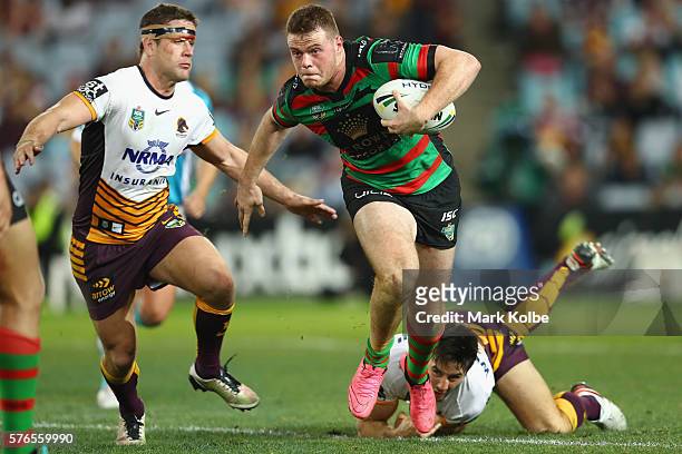Joe Burgess of the Rabbitohs beats the tackle of Andrew McCullough and Ben Hunt of the Broncos during the round 19 NRL match between the South Sydney...