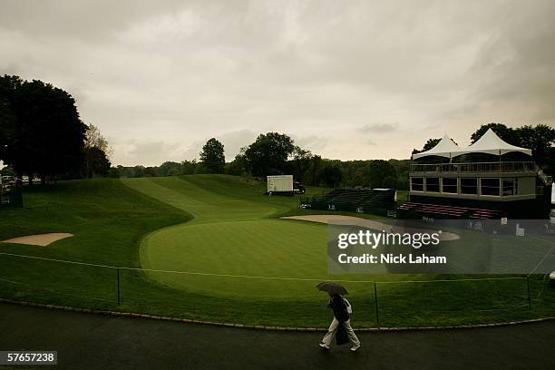 Spectator walks by the 18th green during a rain delay during the second round of the Sybase Classic on May 19, 2006 at the Wykagyl Country Club in...