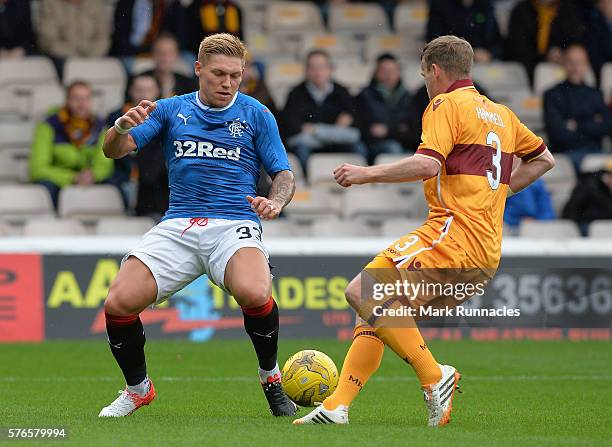 Martyn Waghorn of Rangers is tackled by Carl McHugh of Motherwell during the Scottish League Cup First Round Group Stage match between Motherwell FC...