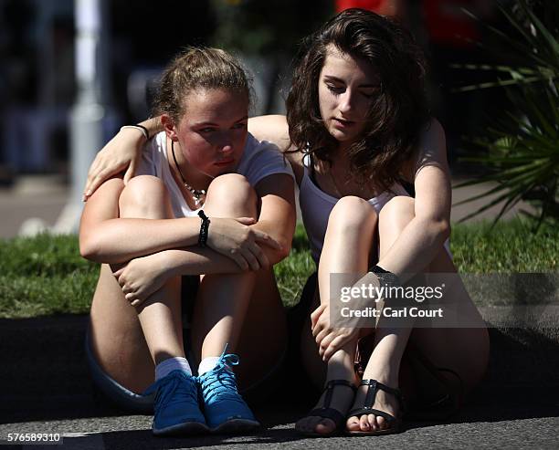 Girls comfort each other as they sit next to flowers laid on the Promenade des Anglais on July 16, 2016 in Nice, France. Five people believed to be...