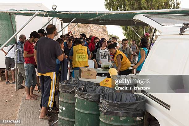 volunteers are serving dinner in greek island refugee camp - quiosque stock pictures, royalty-free photos & images