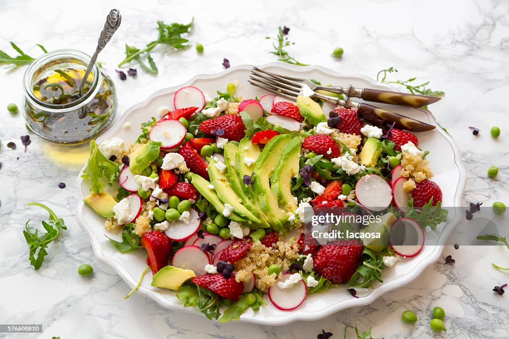 Salad with quinoa, rucola, avocado, radish, strawberries, fetacheese, peas