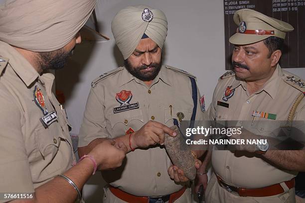 Indian Punjab Police personnel pose with used bomb shell which they found near an Army Cantonement area in Amritsar on July 16, 2016. Punjab police...