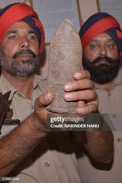 Indian Punjab Police personnel poses with used bomb shell which they found near an Army Cantonement area in Amritsar on July 16, 2016. Punjab police...