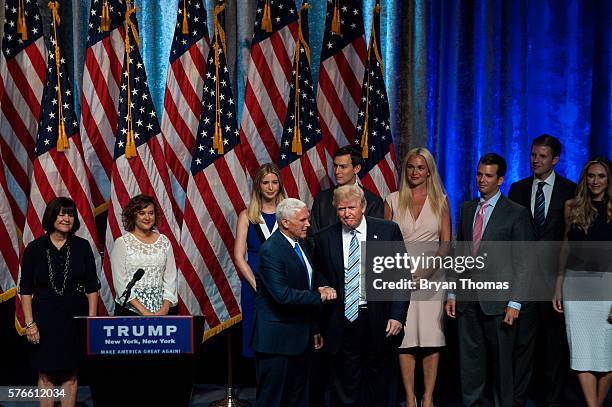 Republican presidential candidate Donald Trump, right, shakes hands with his vice presidential running mate Indiana Gov. Mike Pence, left, as family...