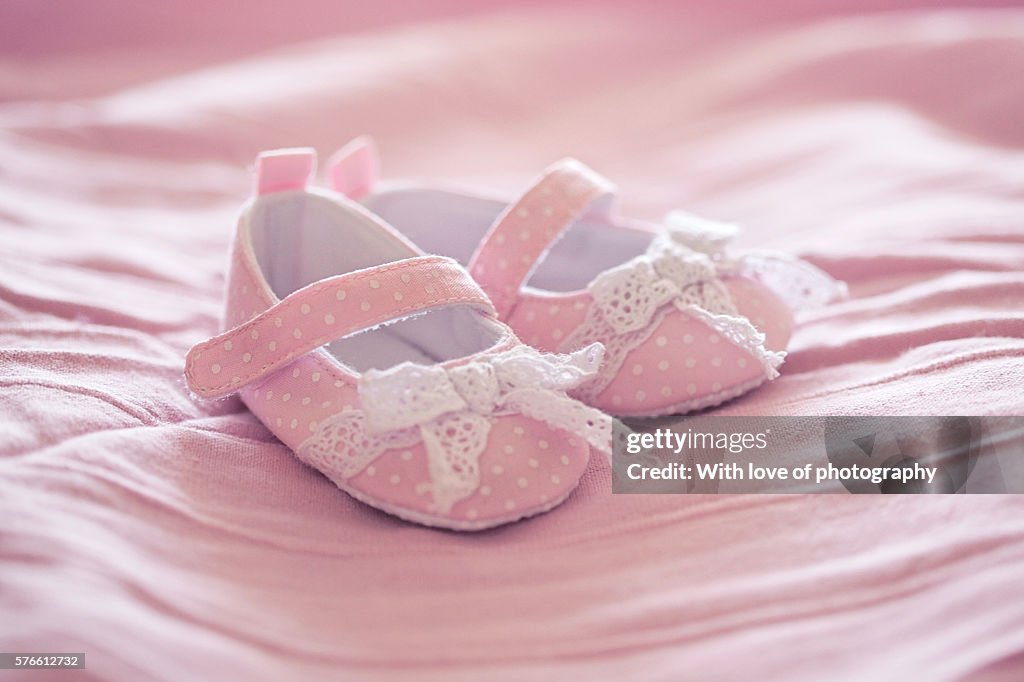 Pink baby shoes on pink blanket. It's a girl!