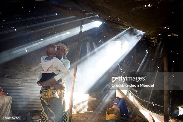 Mathato Notsi with her ten month old baby Mpho in the smoky plastic sheeting shelter which is used as a kitchen at her mother's home. Mathato...