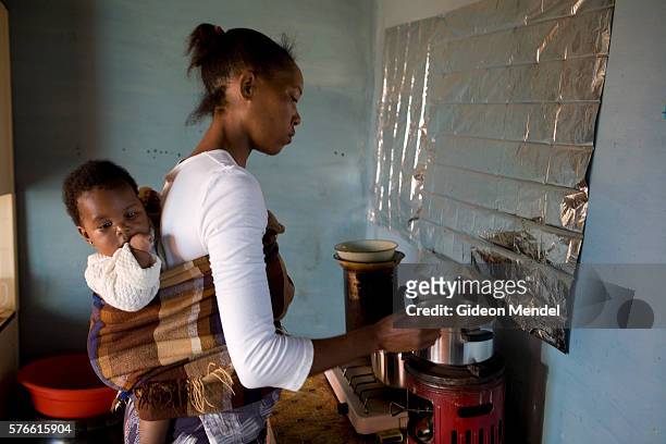 Ntsiuoa Ralefif cooks sorghum porridge with her eight month old baby girl, Nthatisi on her back, at her home in Harom Hapi. . Ntsiuoa found out that...