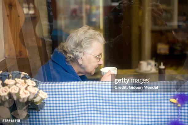 an elderly woman sipping a cup of tea at an old-fashioned english tea room - tea shop stock pictures, royalty-free photos & images