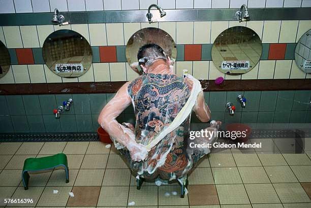 member of yakuza showering in public bath - yakuza stock-fotos und bilder