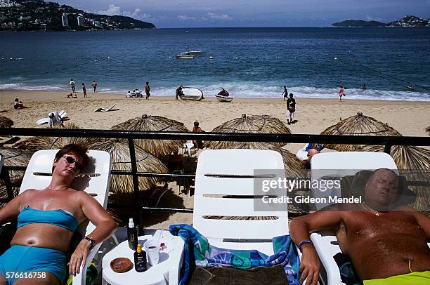 tourists sunbathing near acapulco beach - acapulco chair stockfoto's en -beelden