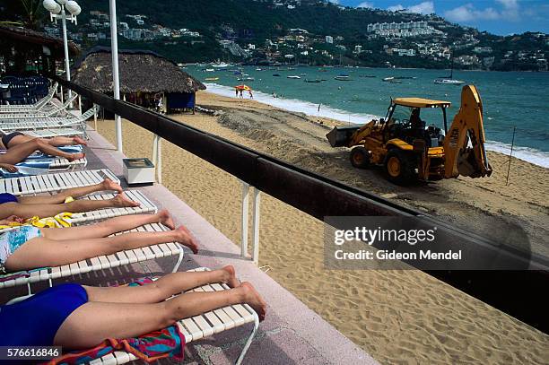 backhoe on beach near sunbathers in acapulco - acapulco chair stockfoto's en -beelden