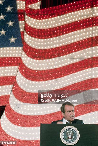 President Richard Nixon gives a speech in front of a huge American flag mural studded with electric lights. The President is speaking at a hotel in...