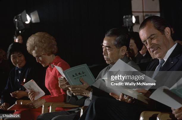 Richard and Pat Nixon sit on either side of Chinese Premier Chou En-Lai, looking at the programs for the soiree they are attending at the Great Hall...