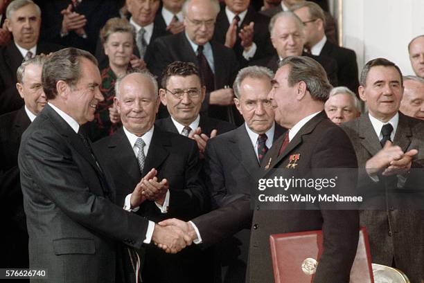 President Richard Nixon shakes hands with Leonid Brezhnev after the signing of the SALT treaty. Among those in the audience, in the front row between...