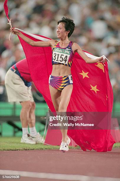 Chinese runner Wang Junxia carries the Chinese flag after winning the gold medal in the 5,000-meter run at the 1996 Atlanta Olympic Games. Junxia...