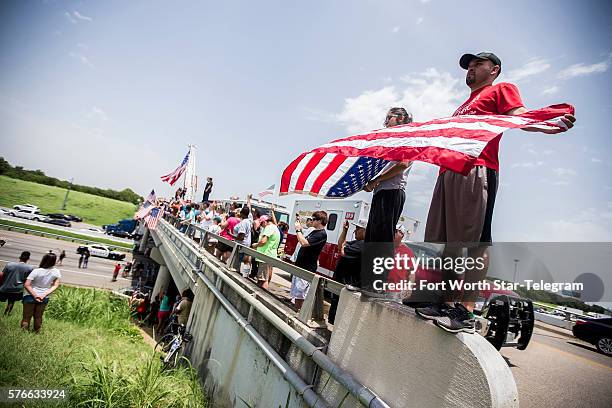 Alfred Mendoza, right, and his daughter, Juliette, hold an American flag as a procession for slain Dallas police officer Patrick Zamarripa travels on...