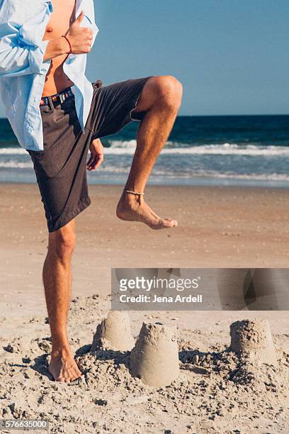 man about to stomp on sand castle - kind sandburg stock-fotos und bilder