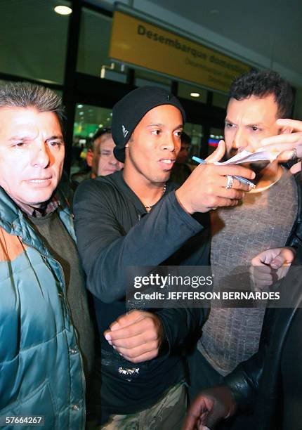 Barcelona's footballer and member of the Brazilian national team Ronaldinho Gaucho , surrounded by security personnel, signs autographs upon his...