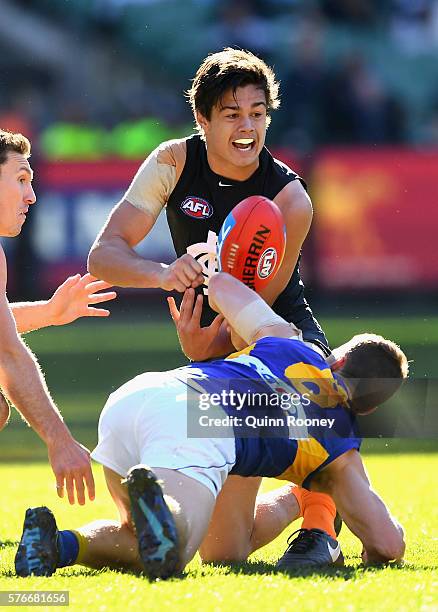 Jack Silvagni of the Blues handballs whilst being tackled by Jack Redden of the Eagles during the round 17 AFL match between the Carlton Blues and...