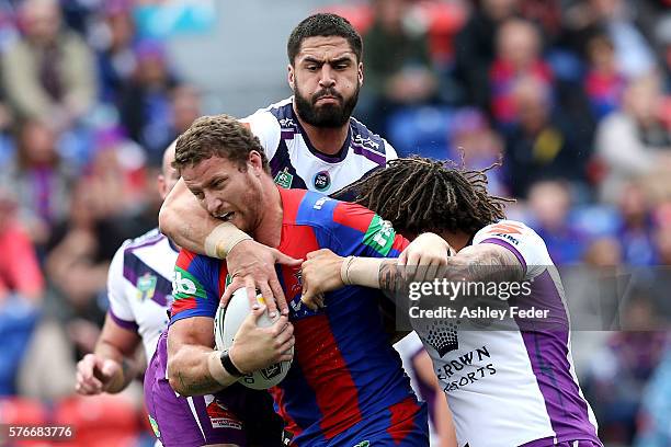 Korbin Sims of the Knights is tackled by the Storm defence during the round 19 NRL match between the Newcastle Knights and the Melbourne Storm at...