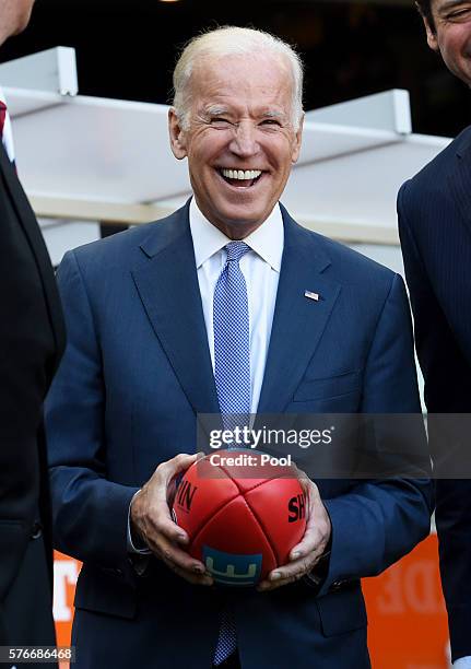 Vice-President Joe Biden holds an AFL football as he speaks to the AFL CEO Gillon McLachlan and Mike Fitzpatrick before the round 17 AFL match...