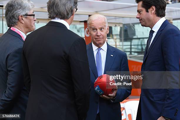 Vice-President Joe Biden holds an AFL football as he speaks to the AFL CEO Gillon McLachlan and Mike Fitzpatrick before the round 17 AFL match...