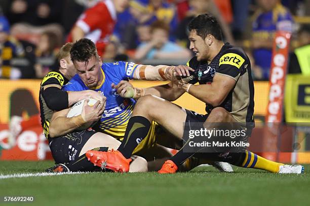 Clinton Gutherson of the Eels is held up over the line by Peter Wallace and Dallin Watene Zelezniak of the Panthers during the round 19 NRL match...