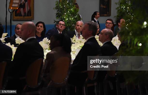 Vice President Joe Biden sits with Victorian Premier Daniel Andrews listen to musician Archie Roach perform during a dinner held by the Governor of...