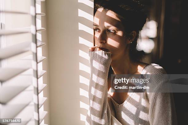 traurige frau blick durch das fenster - beziehungsproblem stock-fotos und bilder