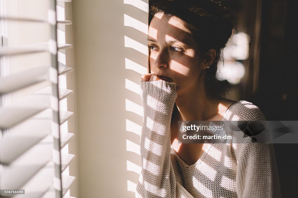 Sad woman looking through the window