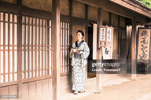 japanische frau mit teetablett vor einem traditionellen japanischen haus - geisha stock-fotos und bilder
