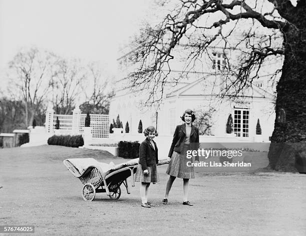 Princess Elizabeth and her sister Princess Margaret pulling a lawn chair on wheels in the terraces at the back of the Royal Lodge, Windsor, UK, April...