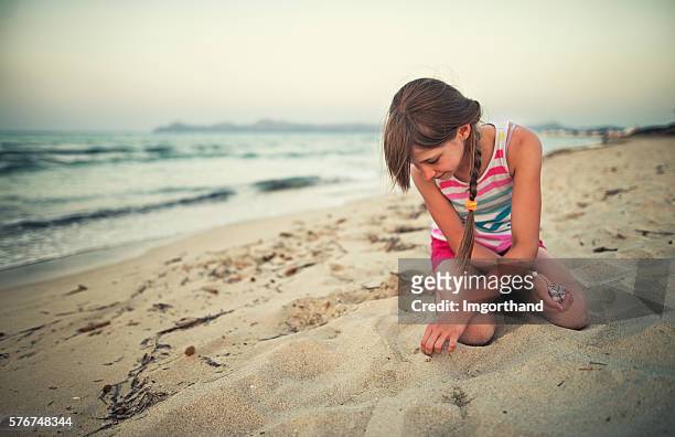 kleines mädchen holt muscheln am strand ab - sea shell stock-fotos und bilder