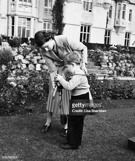Queen Elizabeth II helping Prince Charles with a camera in the grounds of Balmoral Castle, Scotland, 28th September 1952.