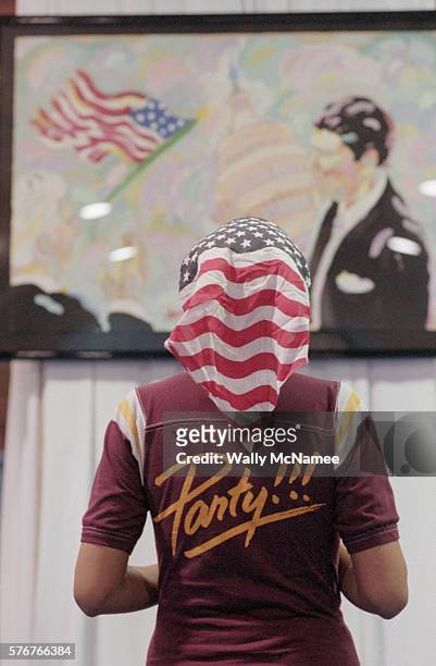 Woman looks a Ronald Reagan mural with a stars and stripes scarf.
