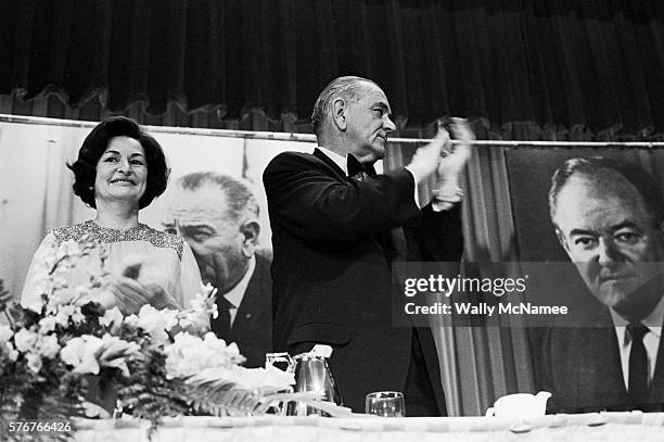 President Lyndon Johnson applauds at a 1967 Democratic Party fundraiser in Washington, DC. His wife, Lady Bird Johnson, stands with him at left.