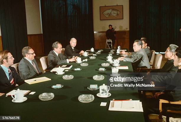 American and Chinese political leaders sit on opposite sides of a table at a meeting during President Richard Nixon's trip to China. On the right are...