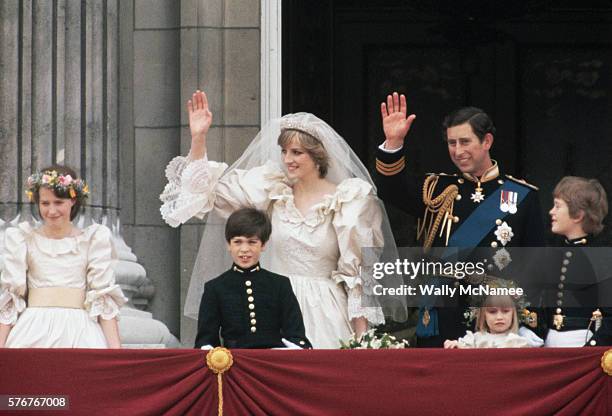 Newlyweds Princess Diana and Prince Charles wave to onlookers from the balcony at Buckingham Palace just after their wedding, attended by young...