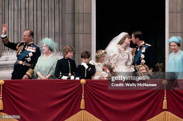 Newlyweds Princess Diana and Prince Charles kiss on the balcony at Buckingham Palace just after their wedding, surrounded by the royal family and...