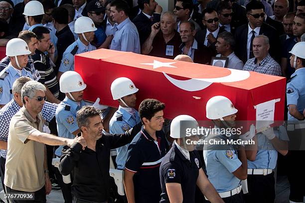 Family members help to carry in the body of a loved one at the funeral for police officers and solidiers killed during Friday's failed coup attempt...