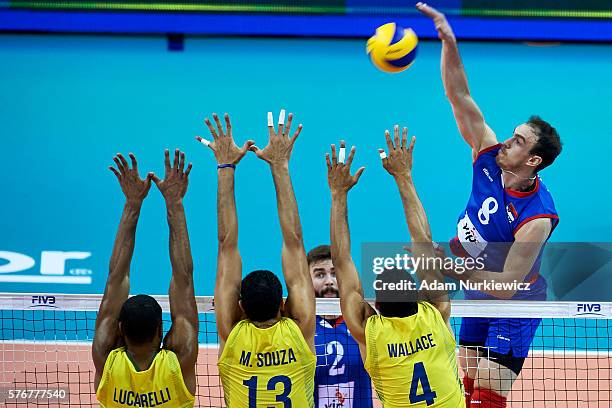 Marko Ivovic from Serbia spikes against Ricardo Lucarelli Santos De Souza from Brazil and Mauricio Souza from Brazil and Wallace De Souza from Brazil...