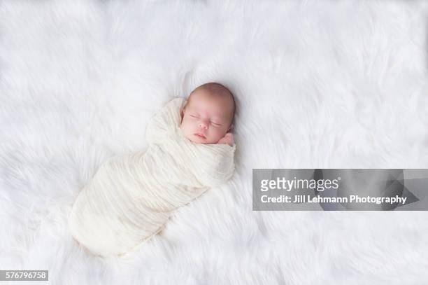newborn sleeps soundly and wrapped in white - shawl stockfoto's en -beelden