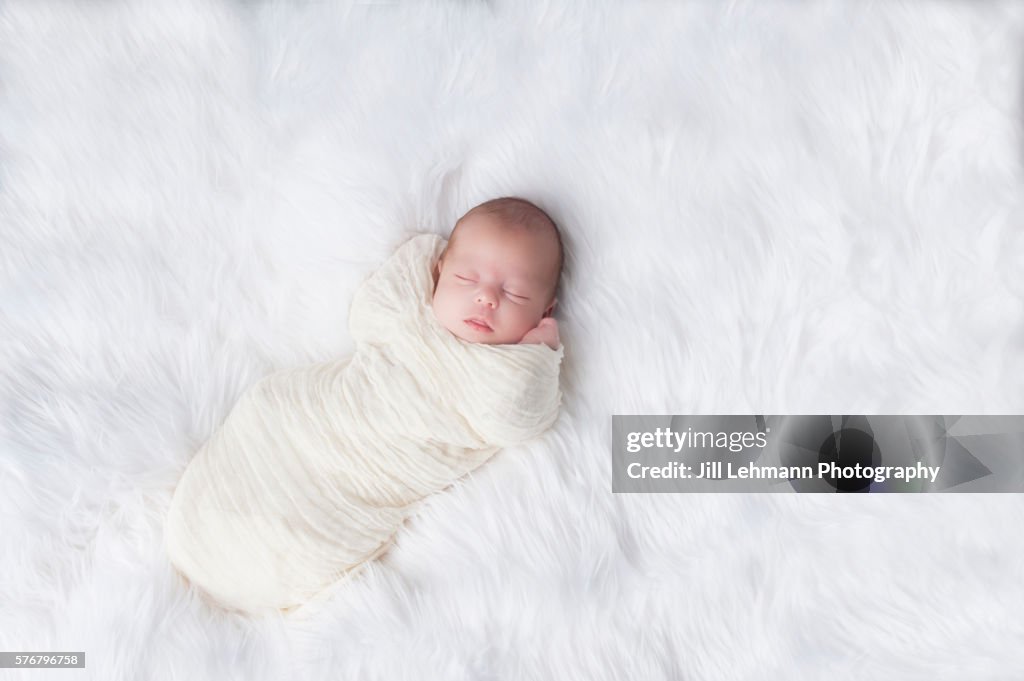 Newborn Sleeps Soundly and Wrapped in White