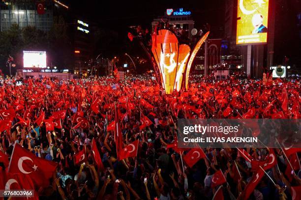 Graphic content / TOPSHOT - Pro-Erdogan supporters wave Turkish flags at Kizilay square in Ankara on July 18, 2016 during a demonstration in support...