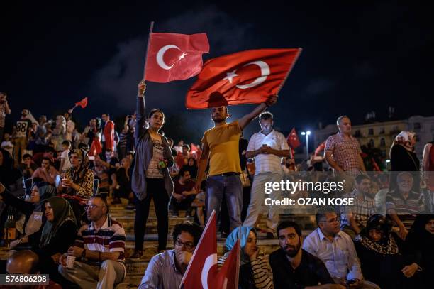 Graphic content / TOPSHOT - Demonstrators wave Turkish flags at Taksim square in Istanbul on July 17, 2016 during a rally in support to the Turkish...
