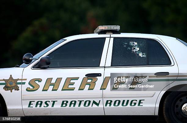 Bullet holes are seen in an East Baton Rouge police car as it's towed away from the scene where three police officers were killed this morning on...