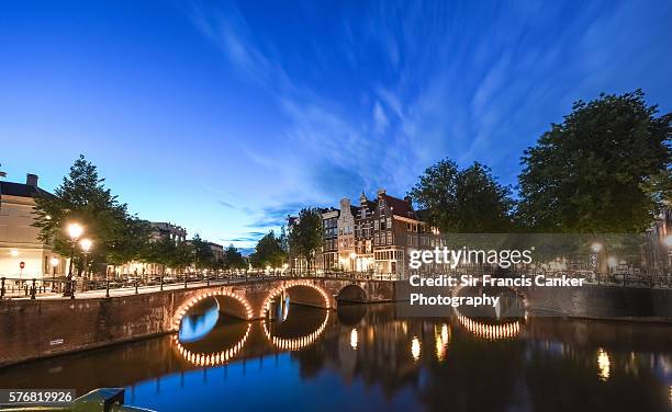 typical dutch bridges illuminated at dusk with perfect reflection on canal, amsterdam - canal disney stock pictures, royalty-free photos & images